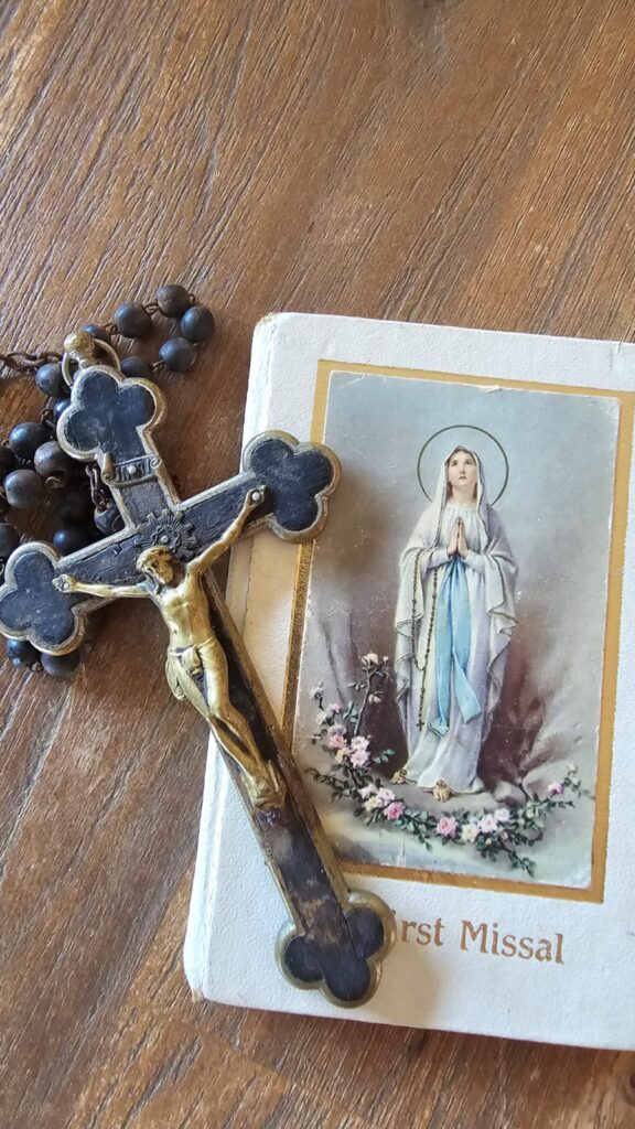 My First Holy Communion missal and my Portuguese grandfather's rosary on a wooden table.